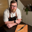 Chef Tom Kirby with Global knife, apron and chopping board.