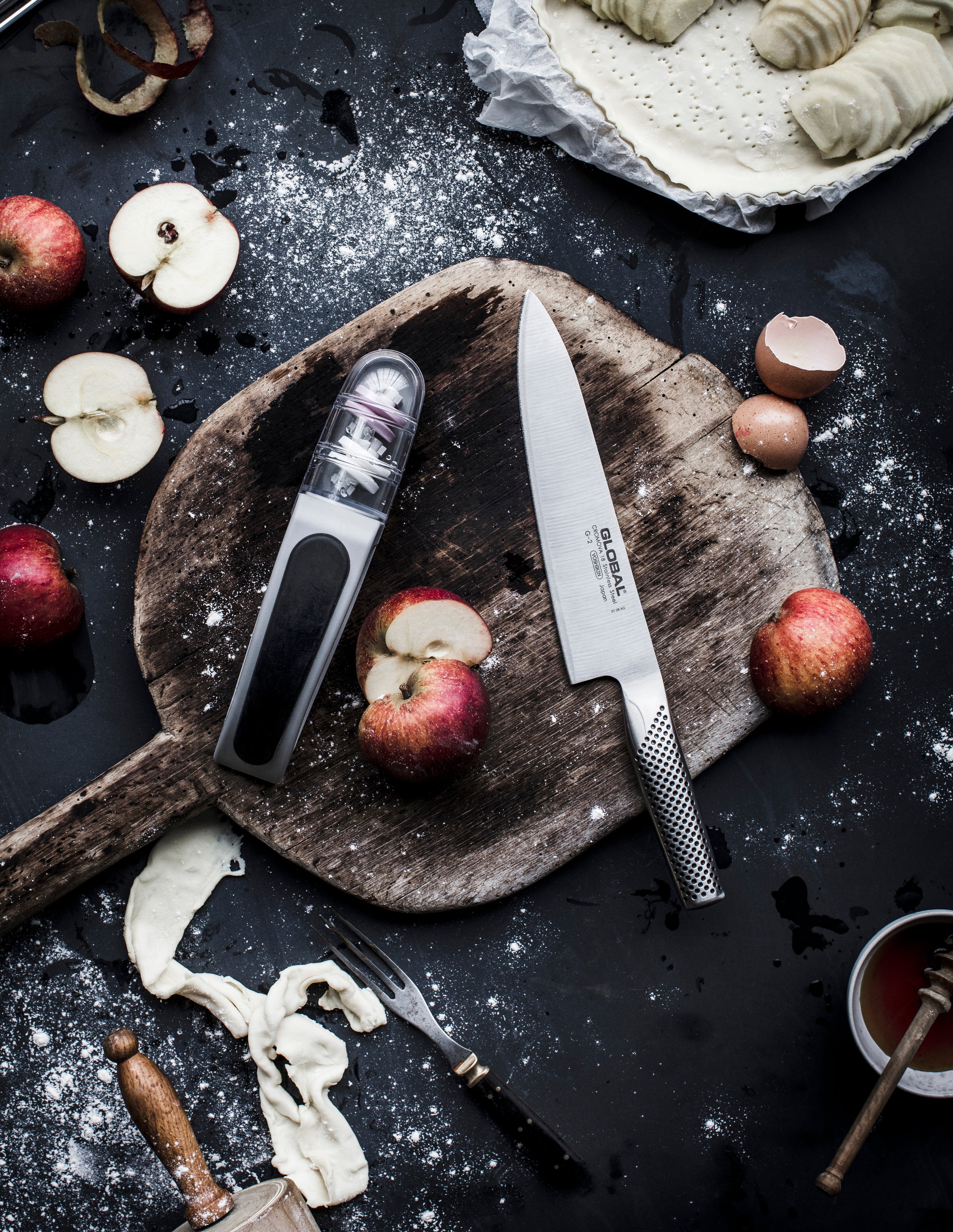 GLOBAL's professional chef's knife next to an easy to use knife sharpener: the GLOBAL pull-through water sharpener with 2 ceramic wheels.
