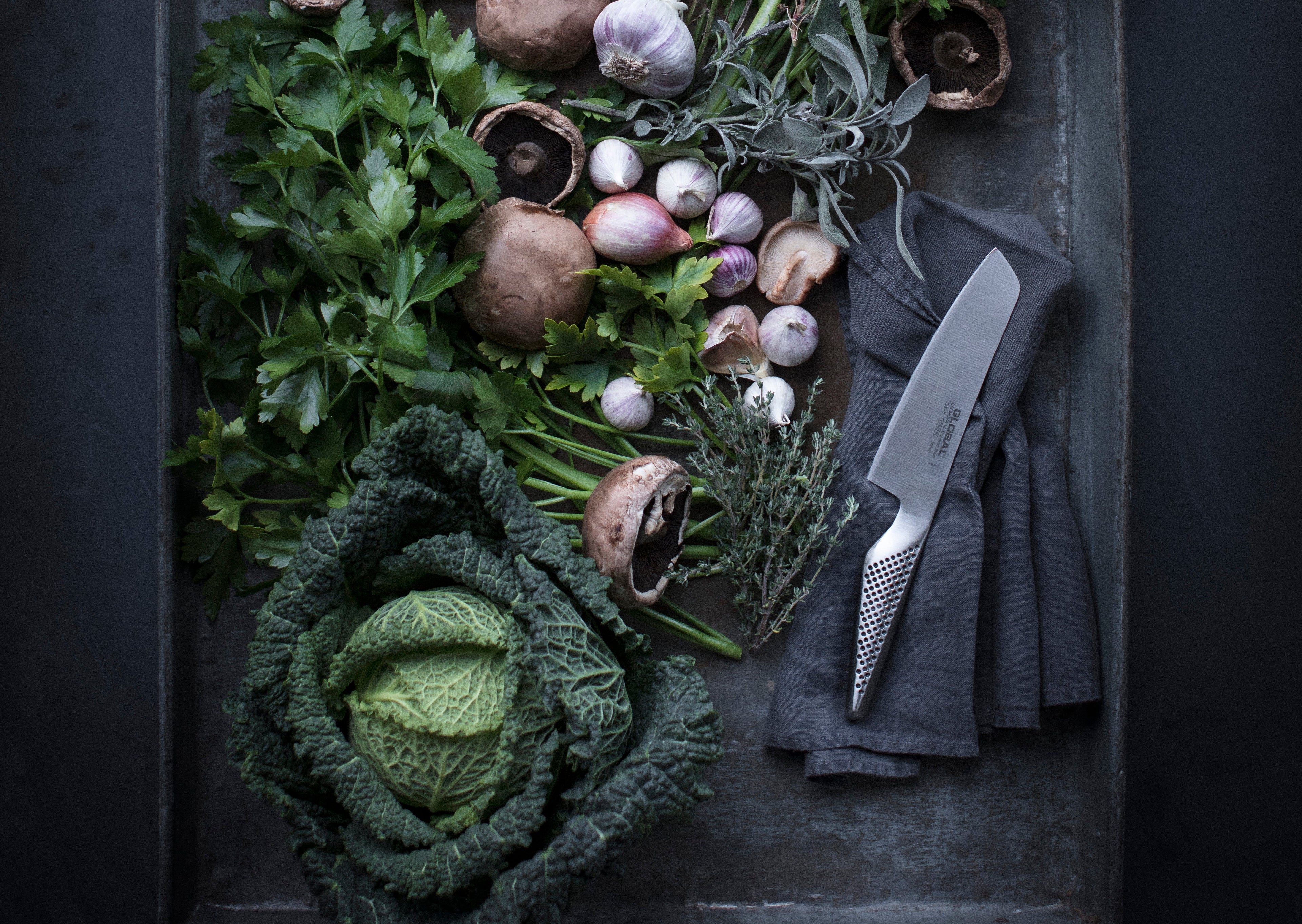 Global vegetable chopping knife on oven tray of vegetables. G-5 vegetable chopper for slicing, dicing and chopping vegetables.