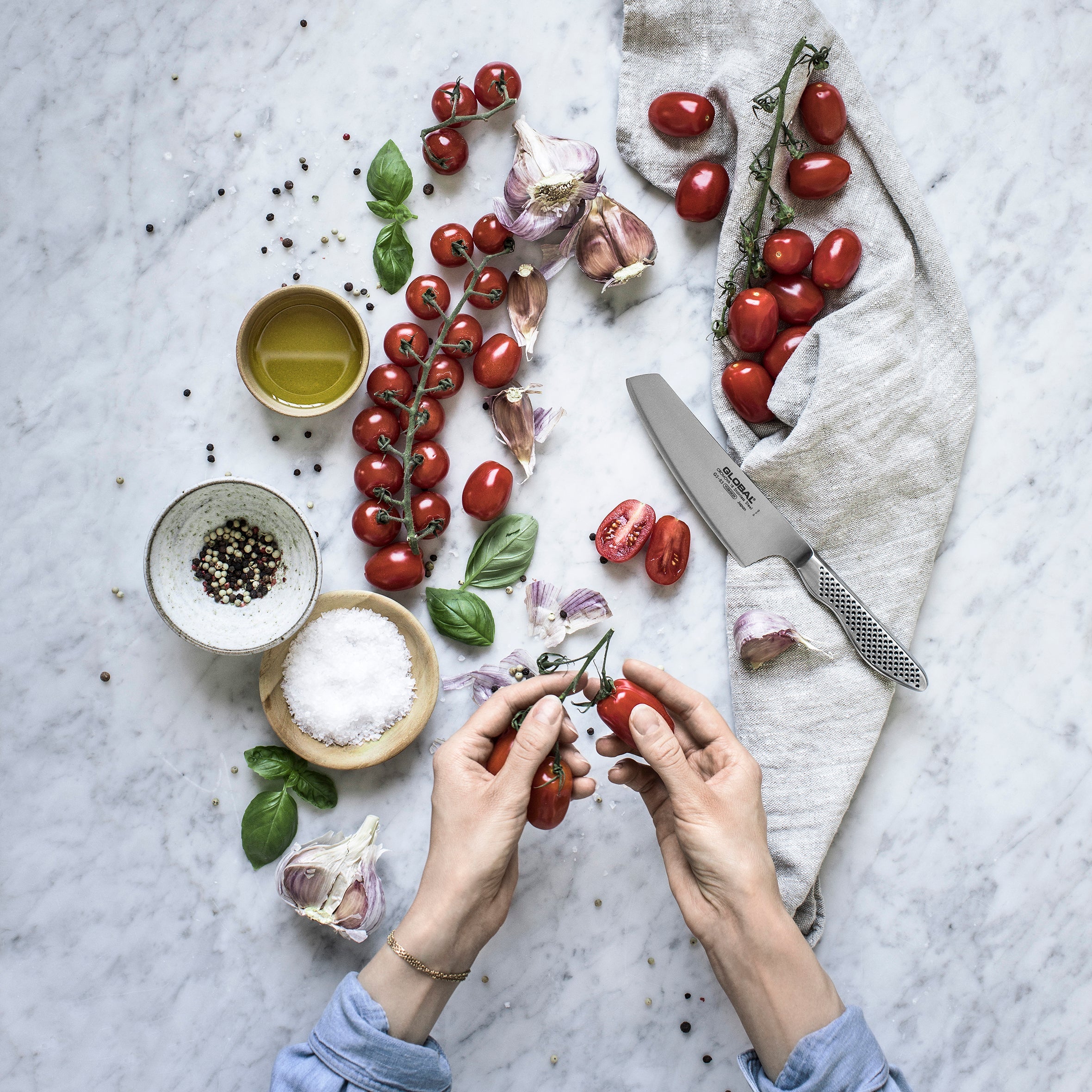 Global GS-83 Usuba Knife for precision cutting and preparing vegetables. Japanese vegetable knife for slicing, dicing and julienning vegetables with clean, thin cuts. Chef preparing tomatoes to effortlessly cut with Global kitchen knife.