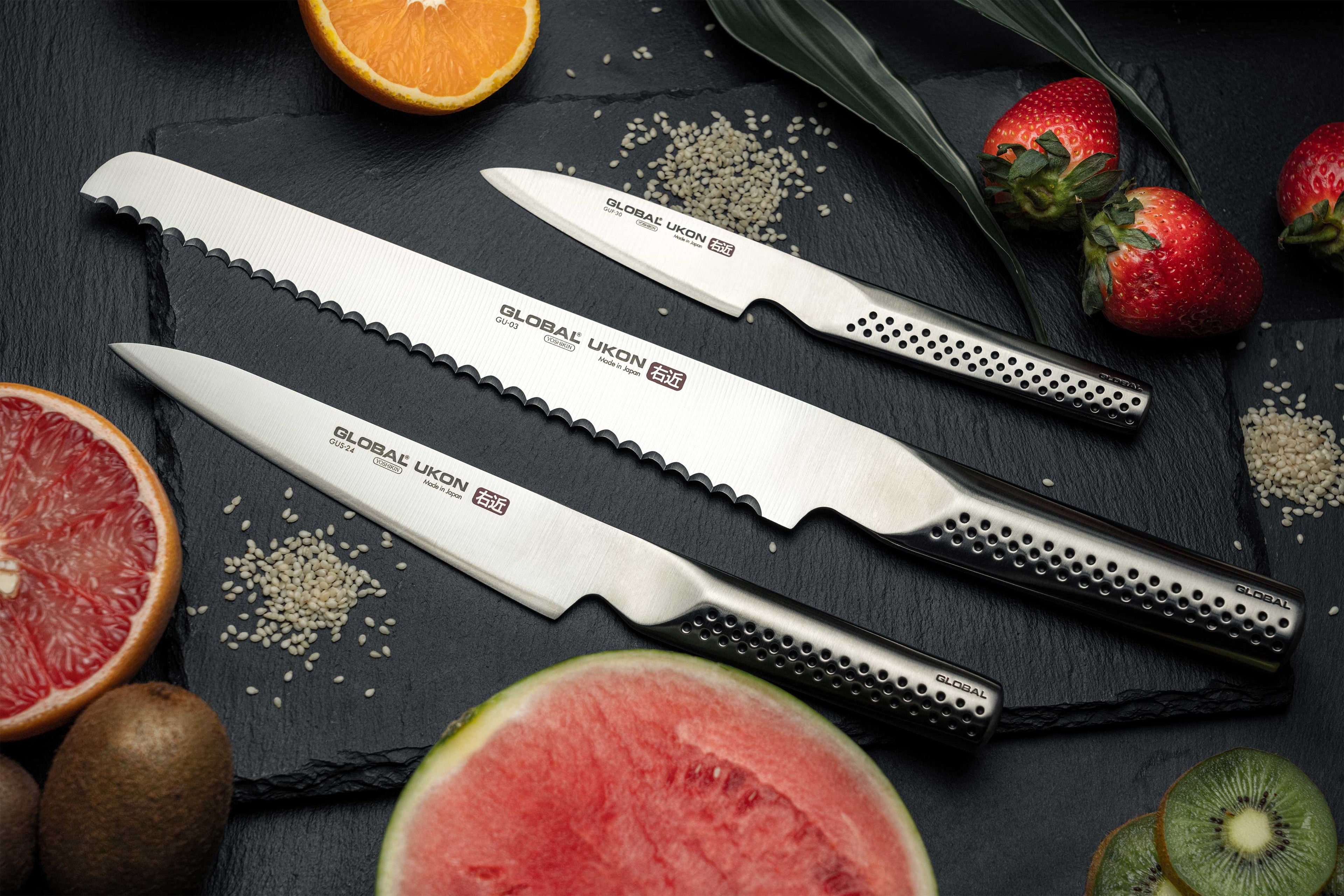 Global Ukon 3 Piece Knife Set on cutting board for slicing water melon, strawberries and kiwis. Luxury kitchen knives next to fruit, perfect gifts for chefs and cooks.