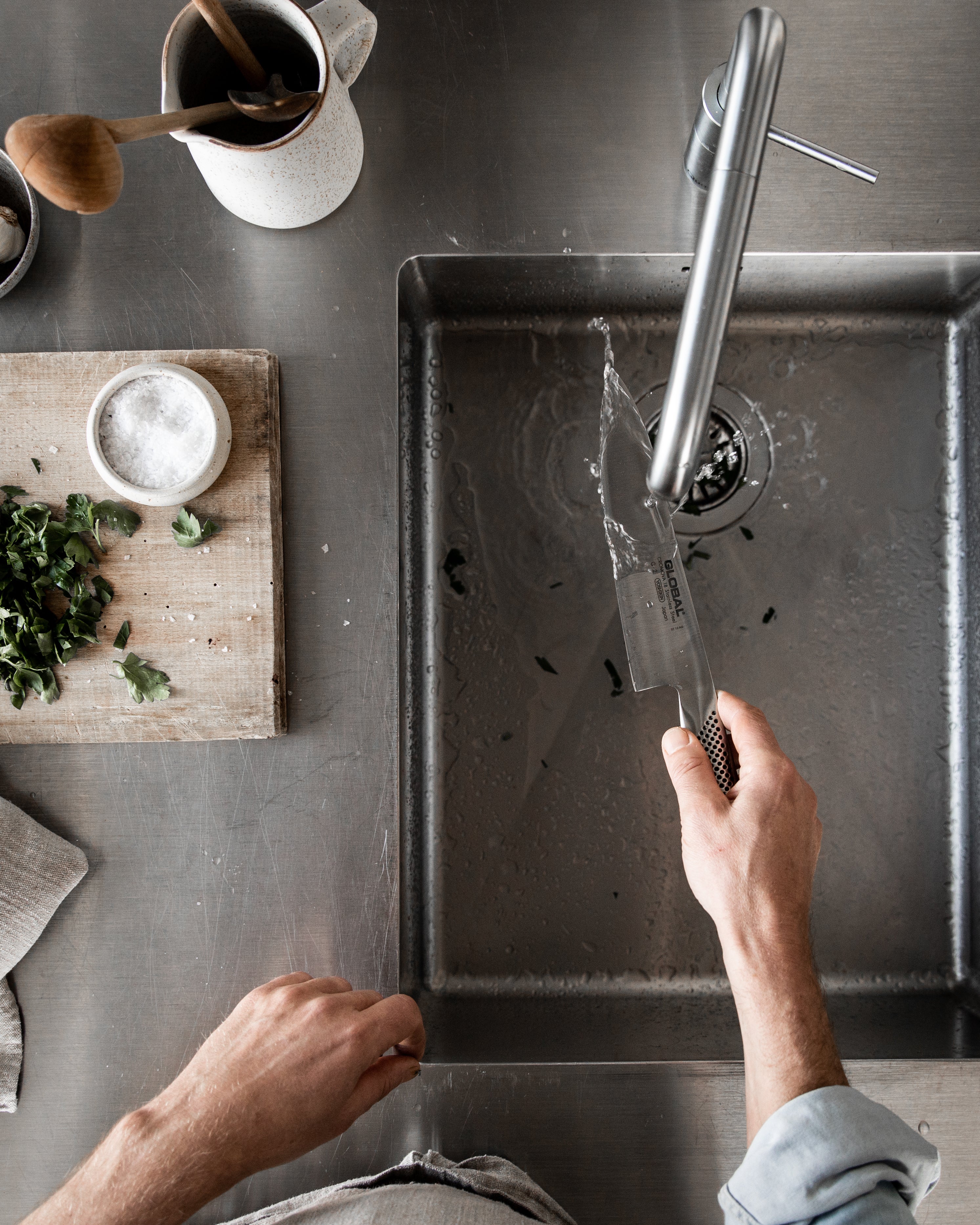 Chef hand washing a GLOBAL G-2 Cook's Knife demonstrating proper knife cleaning and knife maintenance for long-lasting performance.