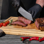 Pitmaster slicing a steak on a wooden cutting board with Global branding using the Global BBQ knife, surrounded by vegetables.