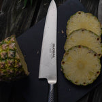 Sliced pineapple on a cutting board with a Global large chef's knife, the global G-16 Cook's Knife