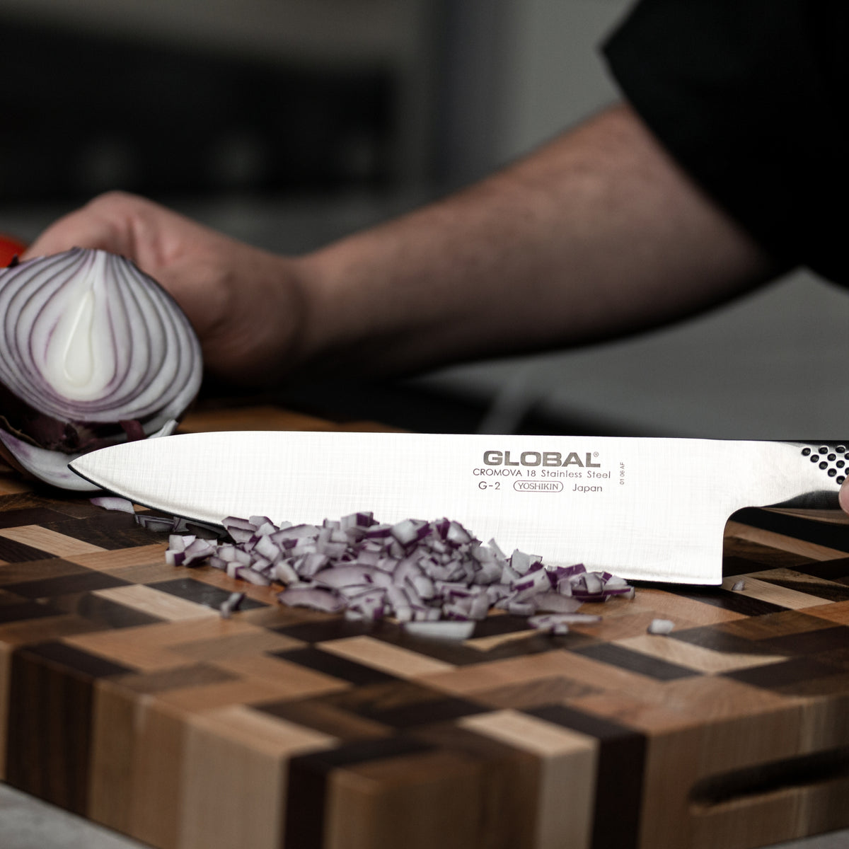 Professional chef using ultra sharp kitchen knife for cutting vegetables. The Global G-2 Cook's knife for cutting onions.