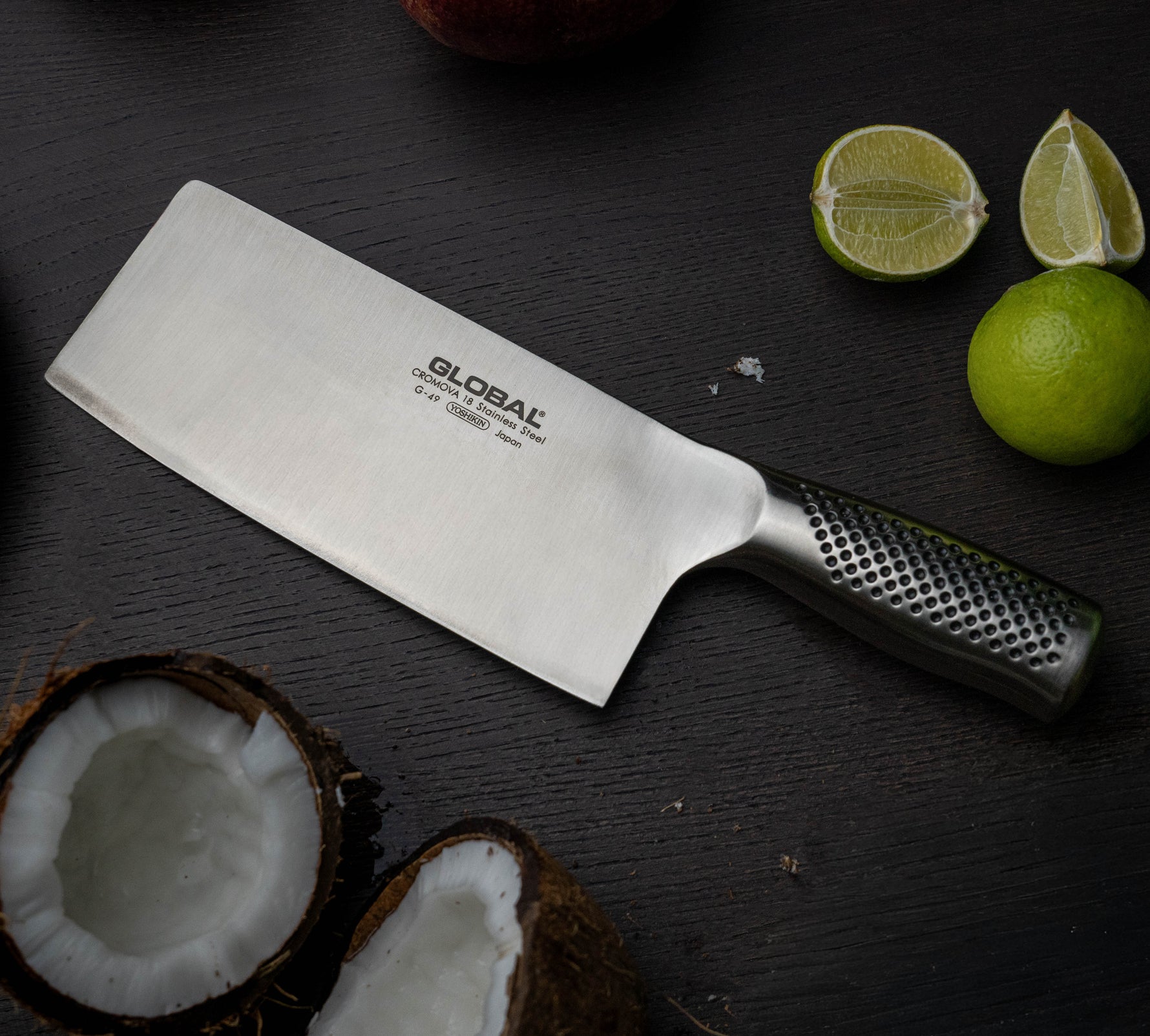 Chinese stainless steel kitchen knife for chopping vegetables, meat, fish and fruit next to chopped lime and coconut.