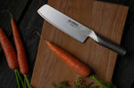 Global Japanese Knife for vegetables on a wooden cutting board with carrots on a dark surface