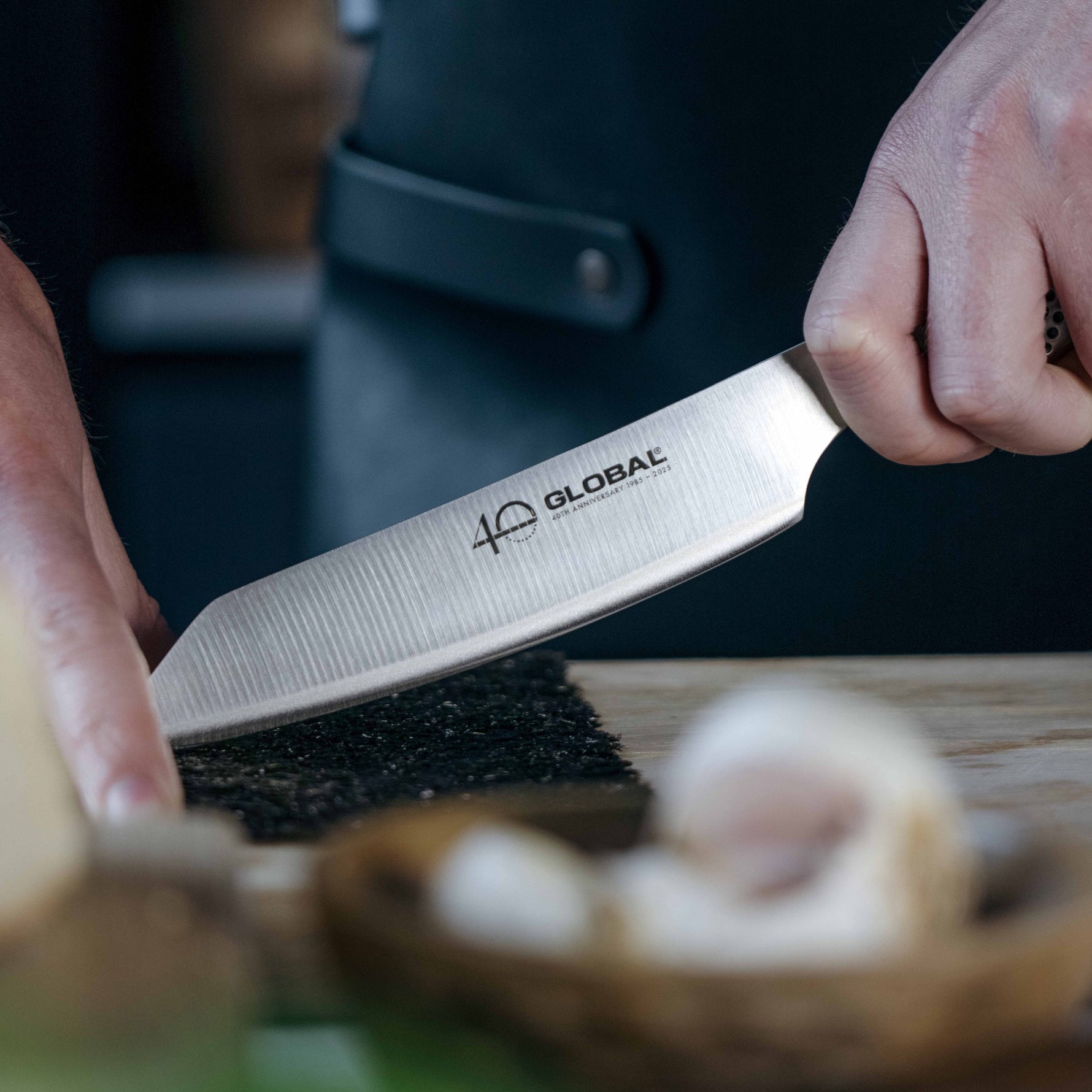 Home cook slicing mushrooms with a Global kitchen knife, the kiritsuke knife, wearing Global leather apron