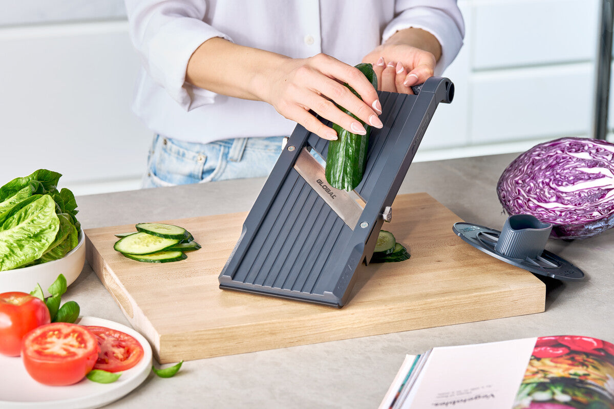 Chef using Global Mandolin slicer for slicing cucumber, cabbage, tomatoes and vegetables into thin, uniform slices. 