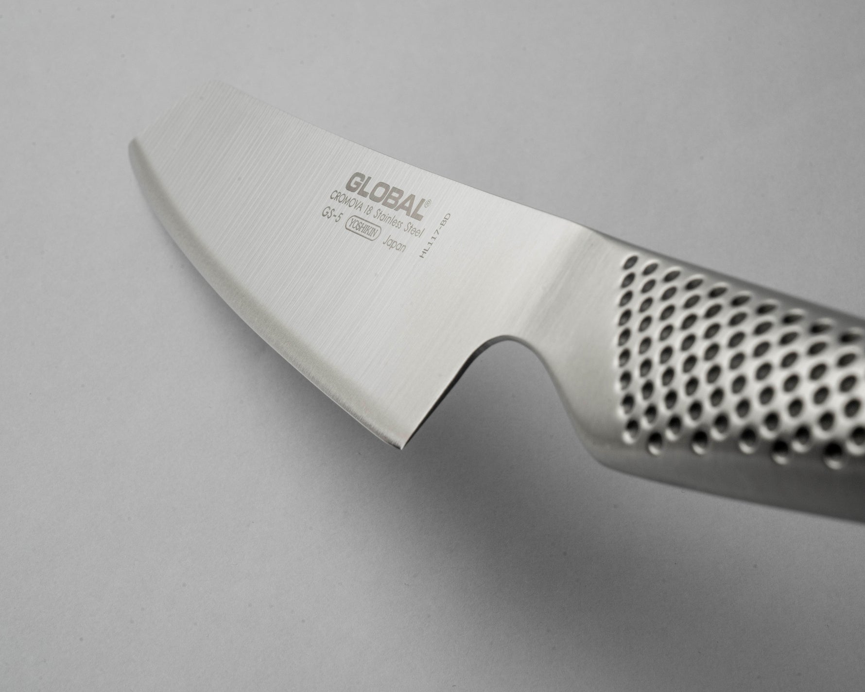 Close-up of a Global knife with a perforated handle on a grey background. Ultra sharp kitchen knife.