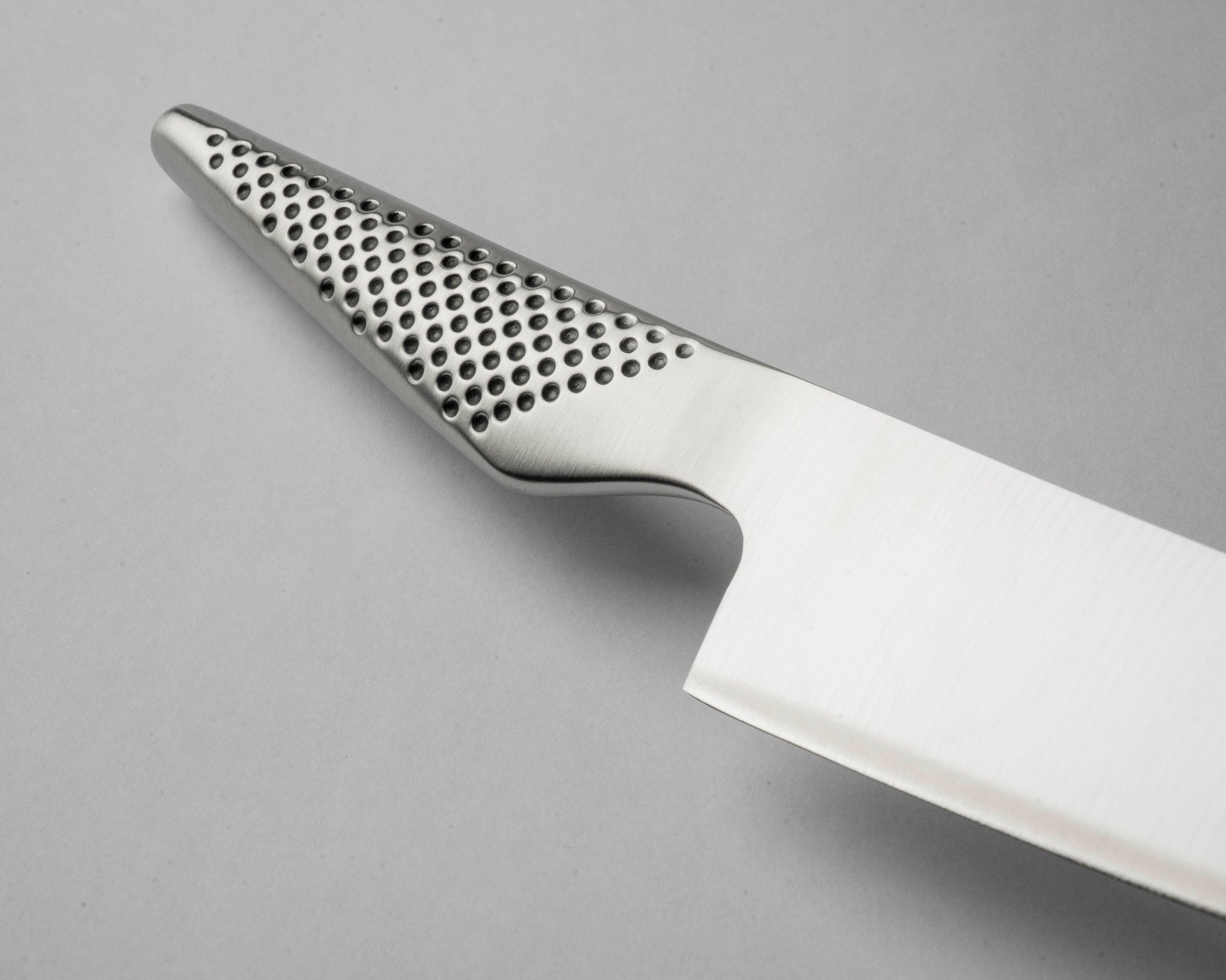 Close-up of a knife with a perforated handle on a grey background. Kitchen knife with ergonomic handle.