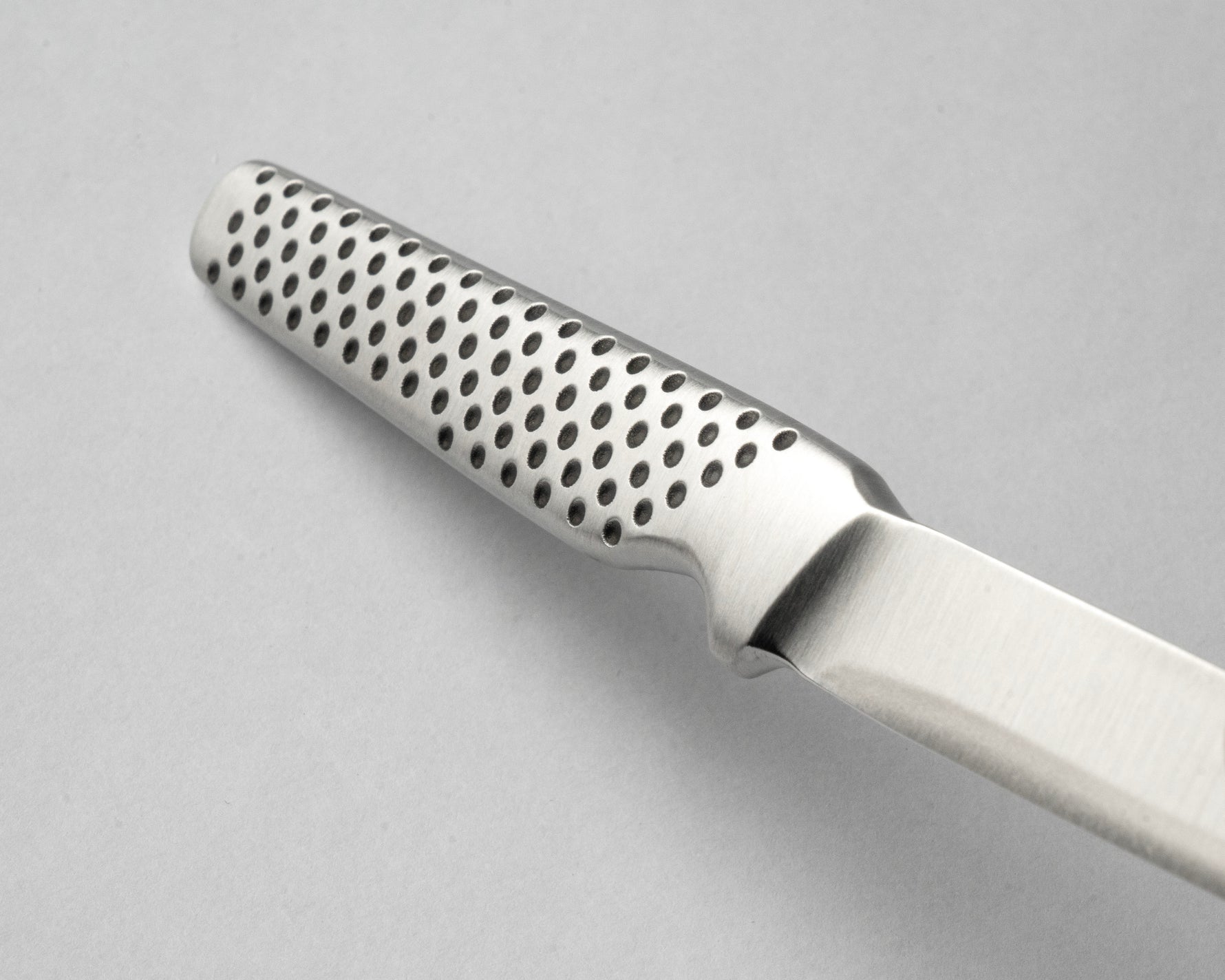 Metallic knife with a textured handle on a gray background, the GSF-15 petty knife.