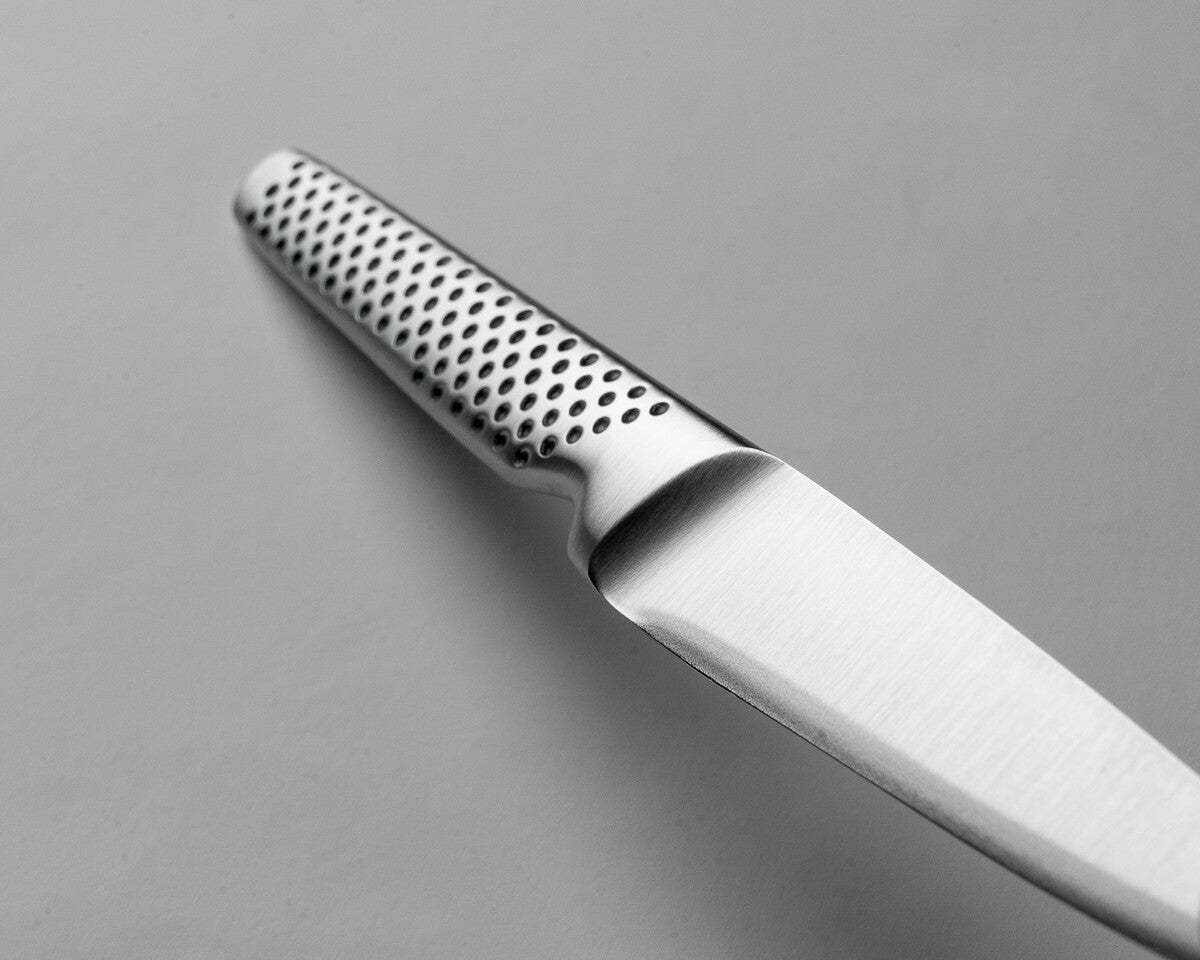 Close-up of the GSF-22 knife blade with a textured handle on a grey background. Shows one piece construction for an easy clean kitchen knife that is hygienic. All stainless steel utility knife.