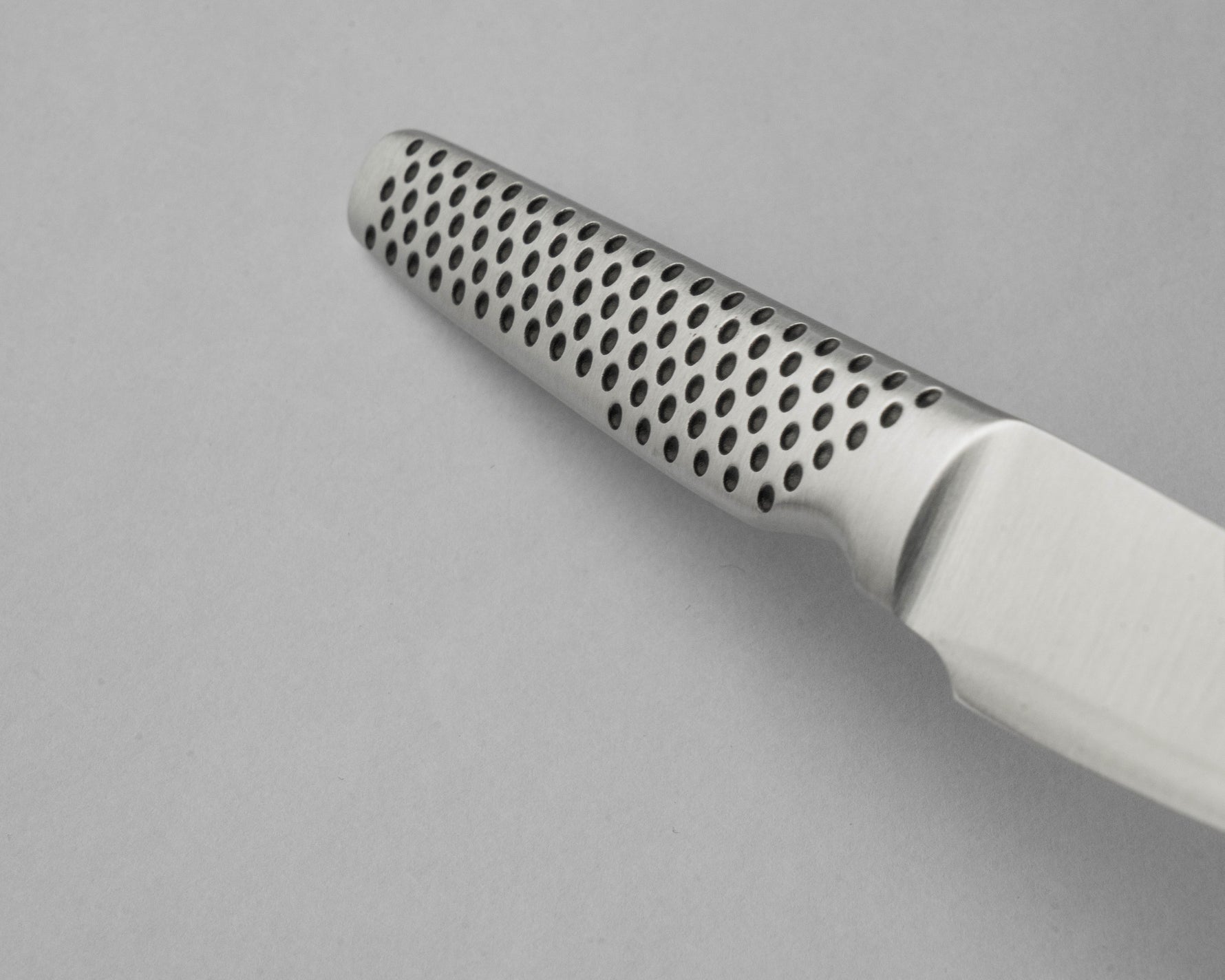 Close up of GSF-46 paring knife with a perforated handle on a grey background