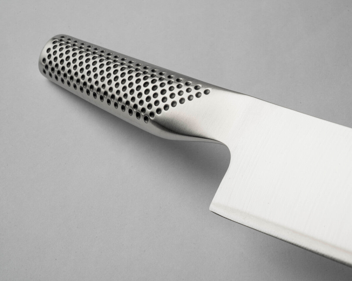 Stainless steel Global G-2 Japanese chef's knife with perforated handle for a comfortable grip on a grey background. Shows Global G-2 Japanese Cook's knife all stainless steel construction for an easy to clean kitchen knife that is hygienic for home and professional kitchens.