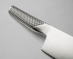 Stainless steel kitchen knife close up of textured handle on a grey background