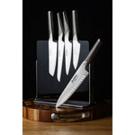 Set of kitchen knives on a wooden magnetic knife holder with a wooden base against a black background. 