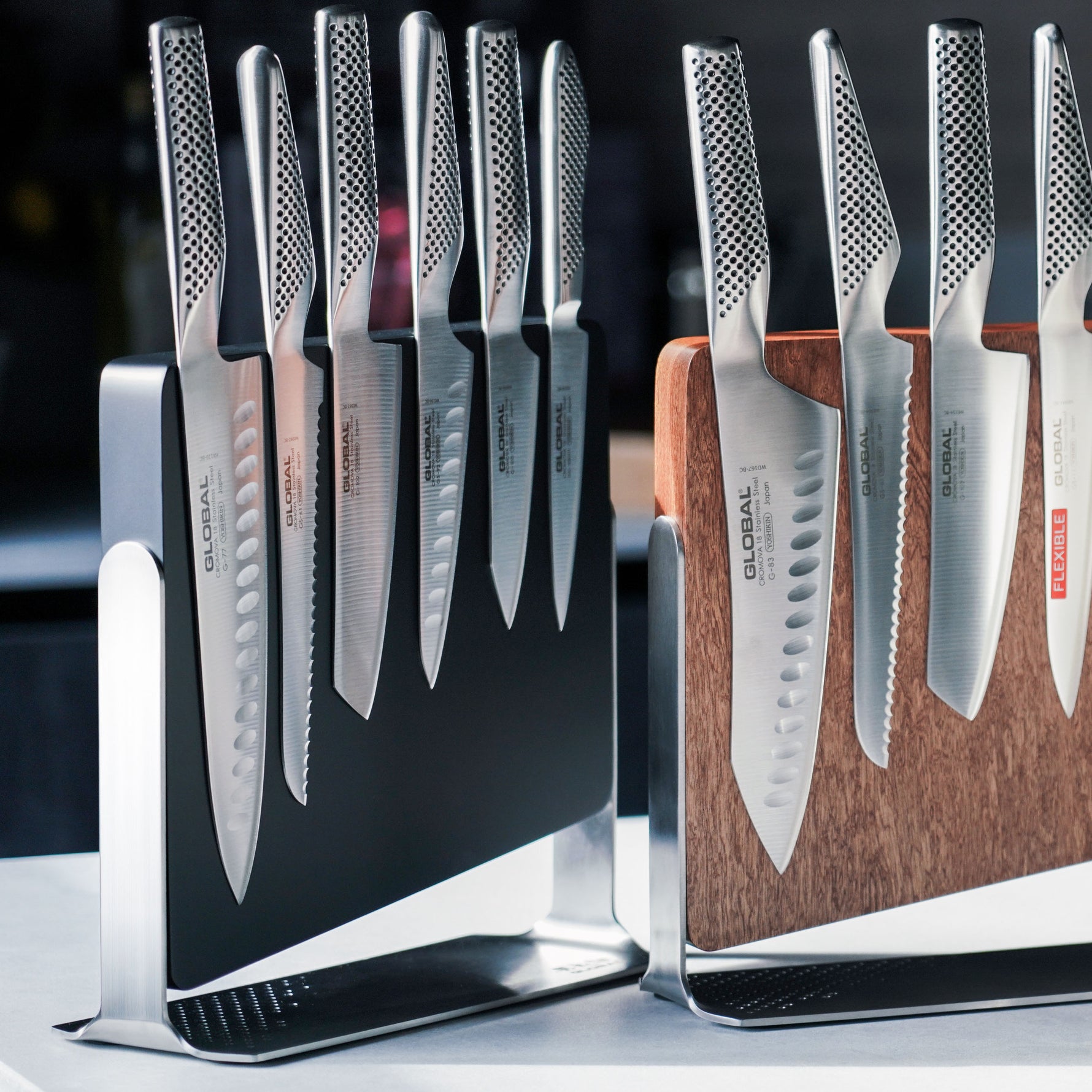 Set of kitchen knives in various types and sizes on stands and a wooden block. Magnetic wood knife blocks with stainless steel kitchen knives made in Japan.