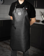 Professional chef wearing Global black leather apron for chefs, durable professional kitchen work ware