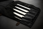 Open black leather knife roll case with 5 slots holding Global Japanese chef knives set