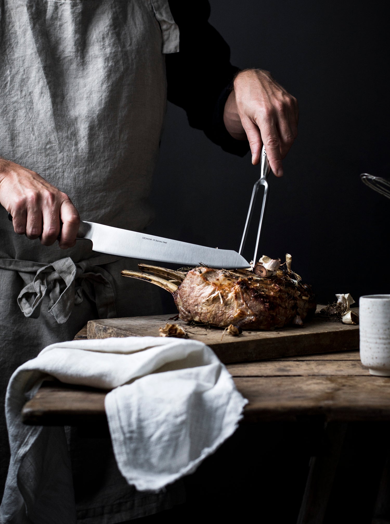 Home cook slicing roast meat with GLOBAL NI Japanese carving knife and fork for controlled, precision slicing when home entertaining.