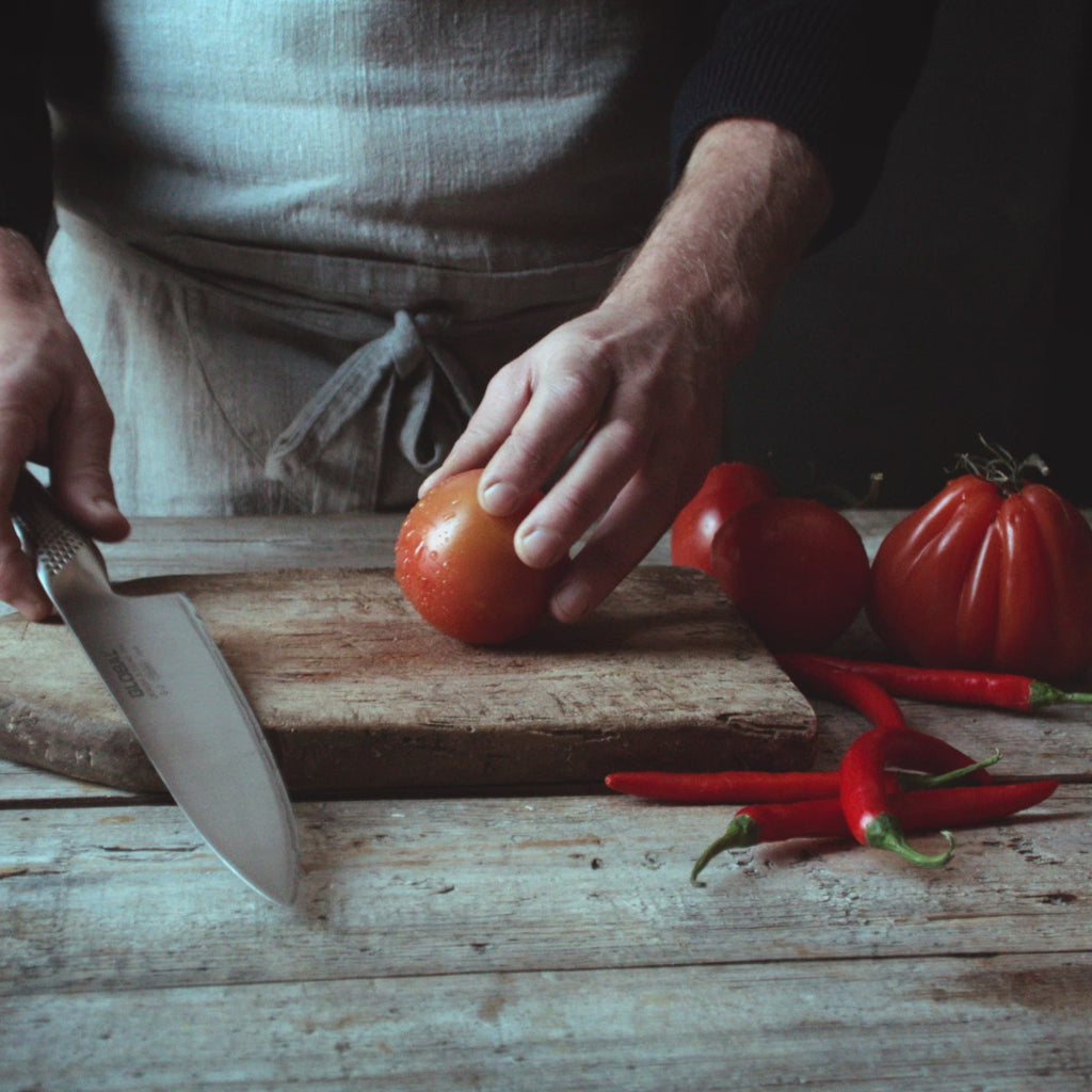 Professional chef using Global G-2 Cook's knife for slicing tomatoes. Ultra sharp kitchen knife for effortless slicing, cutting and dicing.
